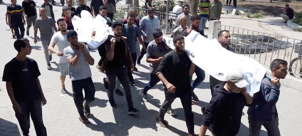 Palestinians inside Gaza's Ahli Hospital carrying the bodies of relatives killed in Israeli airstrikes.