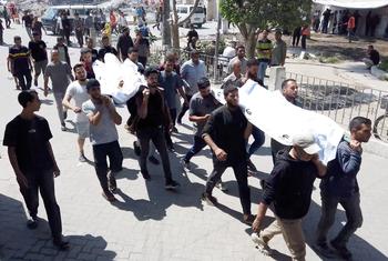 Palestinians inside Gaza's Ahli Hospital carrying the bodies of relatives killed in Israeli airstrikes.