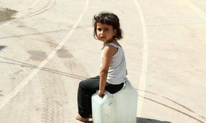 Una niña espera para recoger agua potable en Gaza.