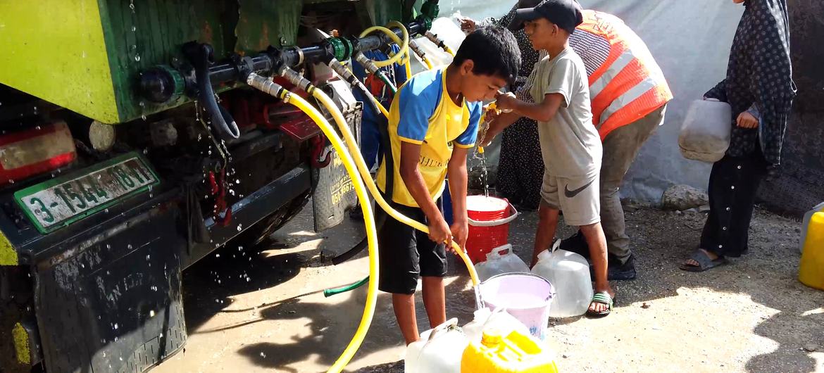Crianças coletam água de um caminhão em um campo de deslocados em Gaza Crianças coletam água de um caminhão em um campo de deslocados em Gaza