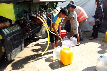 Children collect water from a truck in a displaced persons camp in Gaza. 