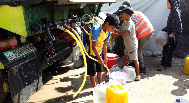 Children collect water from a truck in a displaced persons camp in Gaza. 