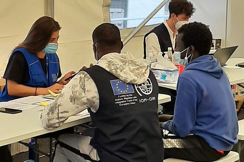 Voluntarios de la OIM ayudan a los migrantes en un mostrador de registro en un centro de acogida en Tenerife.