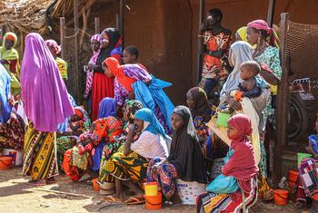 निजेर में, विश्व खाद्य कार्यक्रम (WFP) के एक खाद्य सामग्री वितरण का इन्तेज़ार करते हुए, कुछ महिलाएँ व बच्चे.
