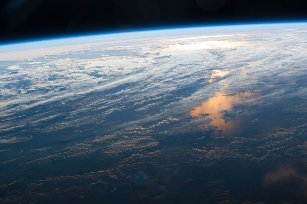 La Tierra vista desde la Estación Espacial Internacional, con la luz del sol abriéndose paso entre las nubes.