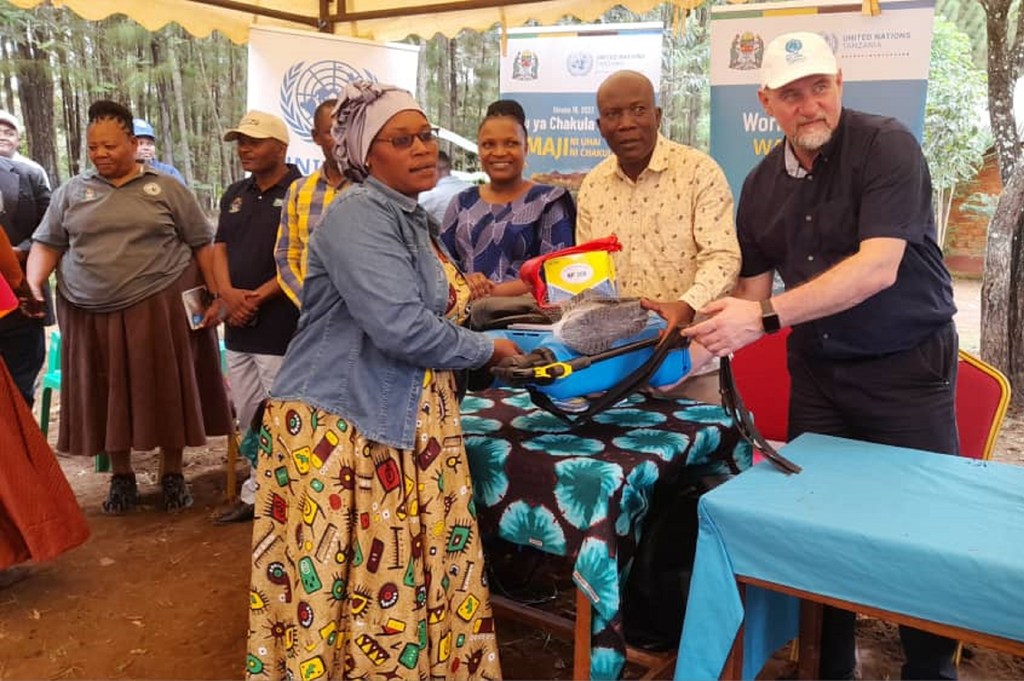 Hadija Alisido kutoka Wilayani Kakonko mkoani Kigoma nchini Tanzania akipokea zawadi za vifaa vya kilimo wakati wa siku ya wanawake wa kijijini. Aliyevaa kofia  nyeupe ni Mwakilishi Mkazi wa Umoja wa Mataifa nchini Tanzania, Zlatan Milišić.