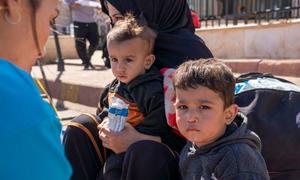Children sit with their mother at the Syrian border after fleeing the escalating violence in Lebanon.