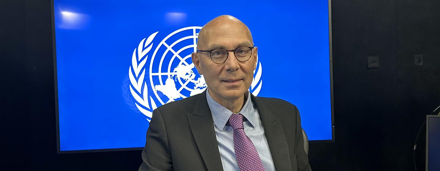 Volker Turk, Secretário-Geral da ONU , durante uma entrevista em estúdio com o logotipo das Nações Unidas visível em uma tela atrás dele.
