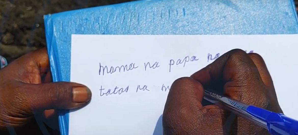 Picha ya karibu ya mikono ya mtu ikiandika kwenye daftari kwa kalamu ya bluu.