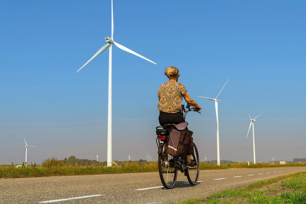 Une femme passe devant des éoliennes sur une route de campagne à Heijningen, aux Pays-Bas.