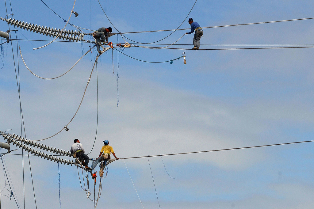 Des ouvriers installent des câbles électriques dans le sud de Luzon, aux Philippines.