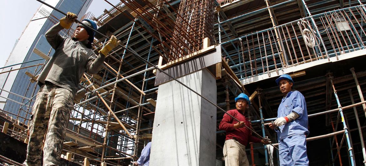 移民工在卡塔尔的一个建筑工地上拽钢筋。