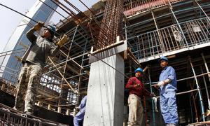 Migrant workers transport metal rods on a construction site in Qatar.