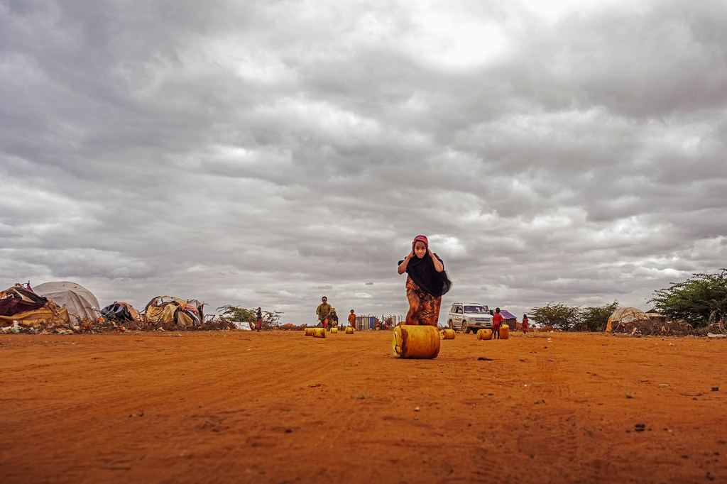 Une jeune fille déplace un conteneur rempli d'eau sur un site pour personnes déplacées à Dolow, en Somalie.