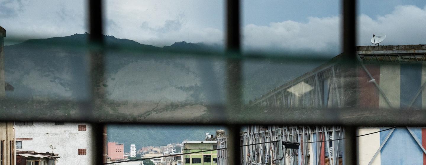 Uma vista de uma rua em Caracas, Venezuela, observando através de uma grade de janelas com montanhas ao fundo.