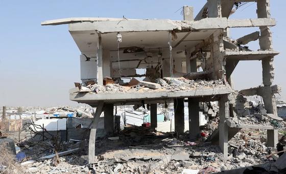 Серьезно поврежденное многоэтажное здание находится на фоне широкомасштабных разрушений в Газе, что подчеркивает опасность, с которой сталкиваются перемещенные семьи, укрывающиеся поблизости.