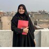 Mwanafunzi mkimbizi wa Rohingya nchini India ameshika daftari jekundu kwenye paa linaloangalia jiji.