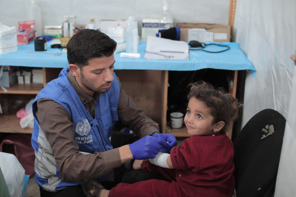 Une petite fille de 2 ans est soignée par un employé de l'UNRWA.