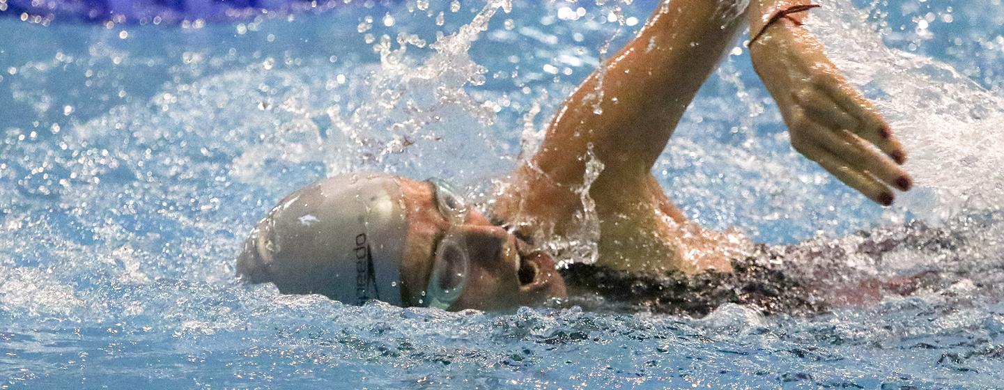 La nadadora Maggie Leri realiza una brazada de estilo libre en una piscina durante una competición de natación.