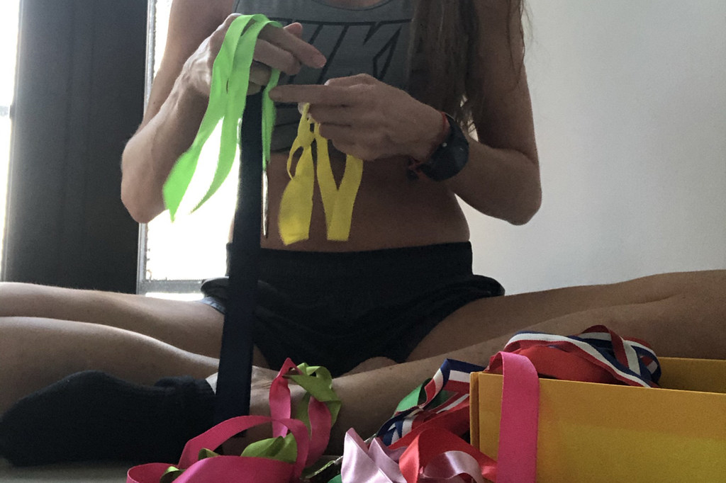 Una mujer con esclerosis múltiple está sentada en el suelo y cuenta medallas con cintas de colores.