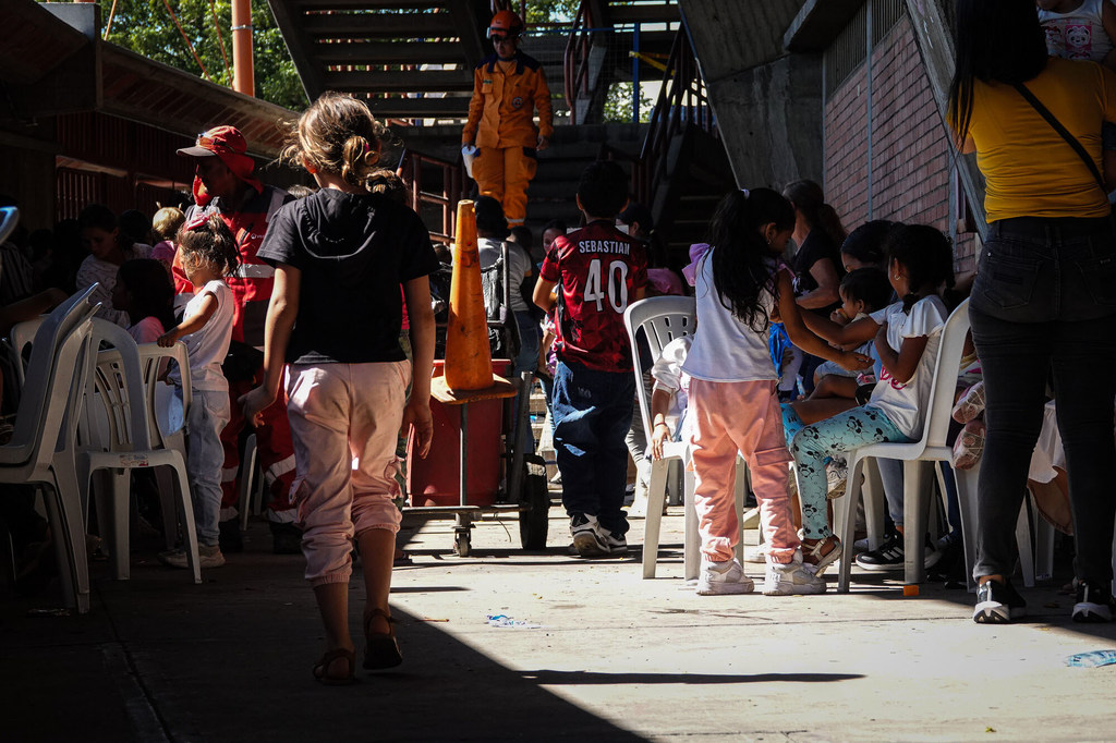 Niños desplazados esperan ayuda en un puesto de socorro al aire libre.
