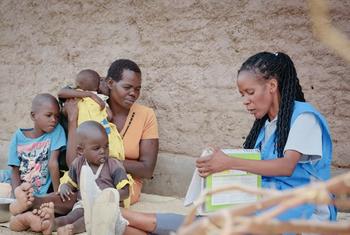 Katika mji wa Lokichar Turkana Kenya, Leah Akiru akiwa ameketi nje ya nyumba yake na watoto wake akipatiwa mafunzo na mhudumu wa afya wa UNICEF.