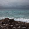 Les vagues s'écrasent contre un littoral rocheux en Libye, sous un ciel sombre et nuageux qui recouvre la mer Méditerranée.