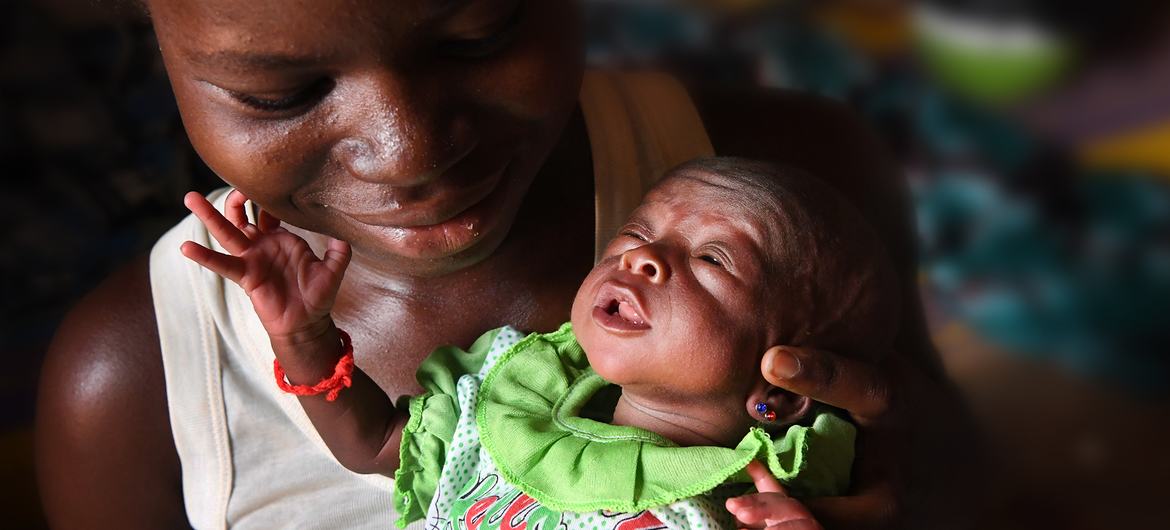 在布基纳法索中北部地区，一名流离失所的年轻妇女抱着刚出生的婴儿。