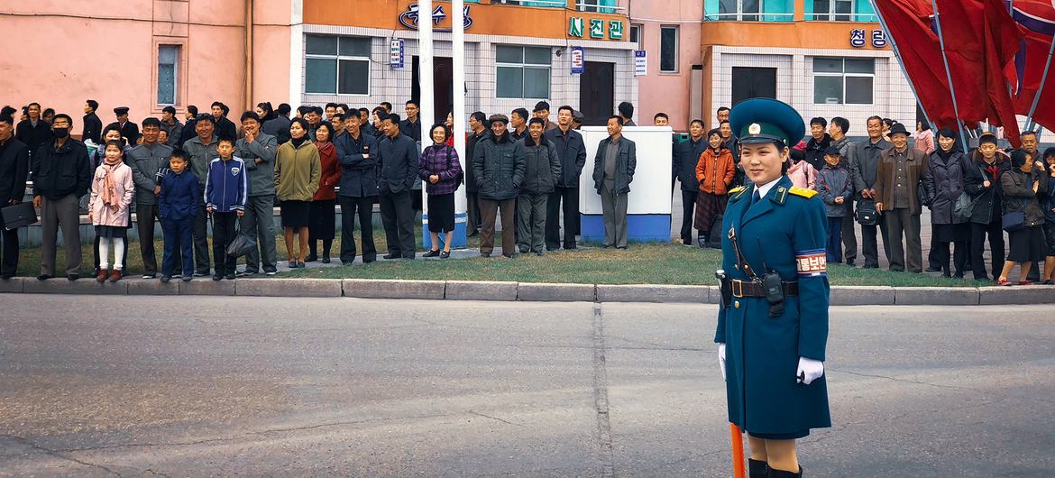 Residents of Pyongyang, DPRK, wait to cross the road.
