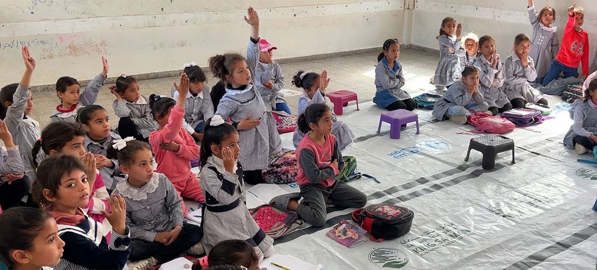 تلاميذ المدارس يرفعون أيديهم في فصل دراسي في غزة.
