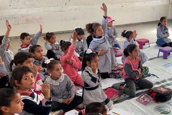 تلاميذ المدارس يرفعون أيديهم في فصل دراسي في غزة.