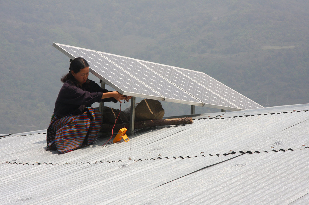 Une femme installe un panneau solaire au Bhutan