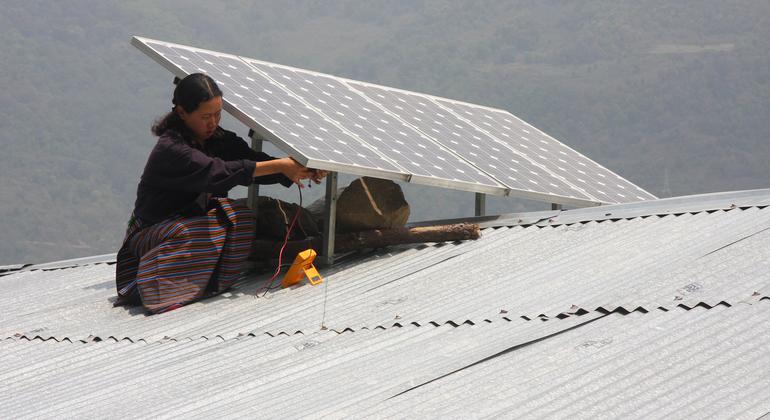 Жительница Индонезии устанавливает солнечную батарею на крыше дома. 