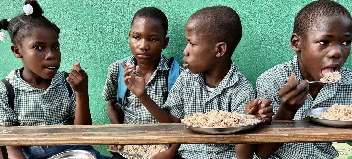 Crianças no Haiti comem uma refeição fornecida como parte do programa de alimentação escolar do PMA.