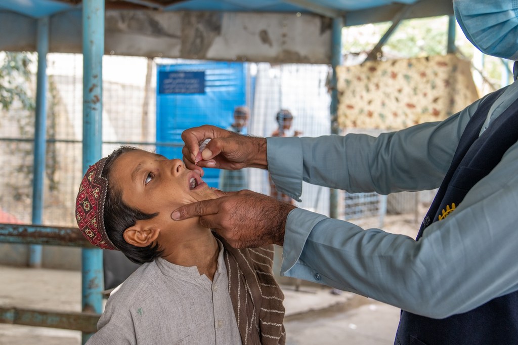 अफगानिस्तान के नांगरहार प्रांत में एक टीकाकरण केंद्र पर एक स्वास्थ्यकर्मी द्वारा एक छोटे लड़के को पोलियो का मौखिक टीका लगाया जा रहा है।