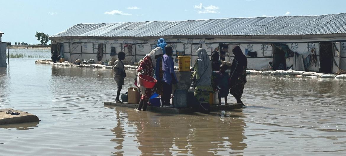 Families wade through floodwaters to access a water point at a site for internally displaced people in Dikwa in Nigeria's north-eastern Borno State.