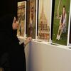Uma mulher com hijab e abaya observa retratos de trabalhadoras domésticas expostos em uma exposição da OIT no Catar.