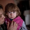 Dans l'est de l'Ukraine, une mère tient sa fille dans ses bras dans la tour d'habitation partiellement détruite où elles vivent encore.