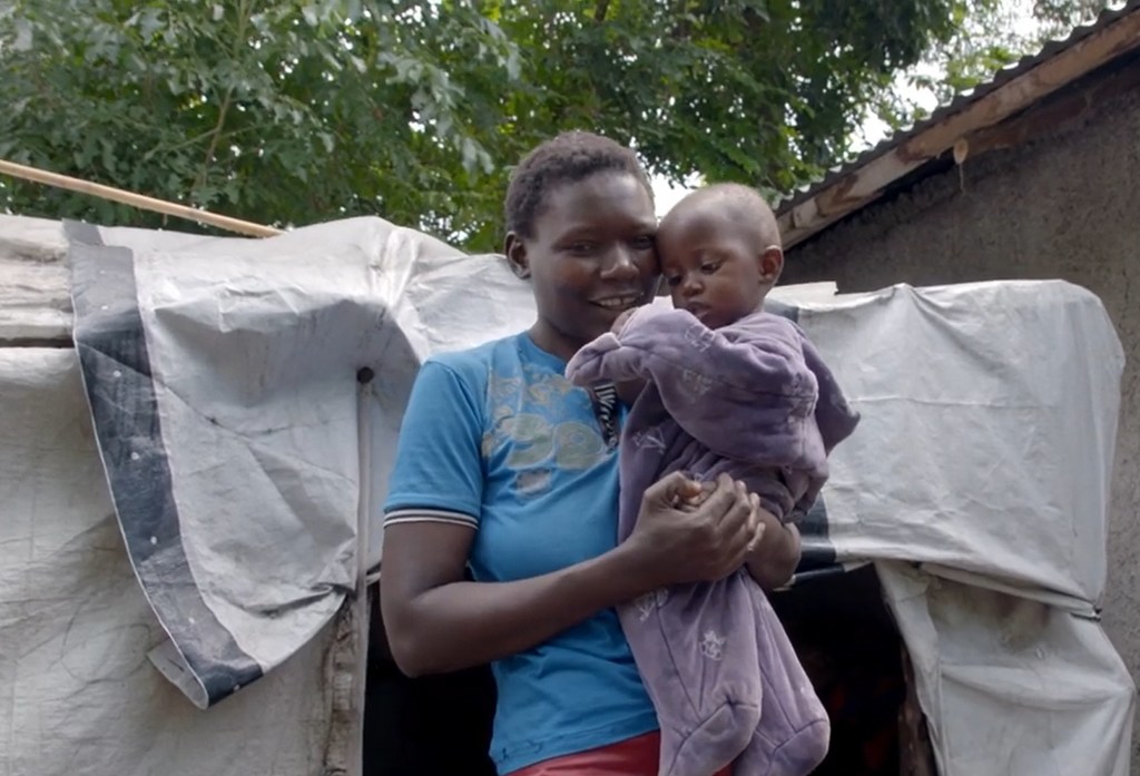 Beatrice Nabwire Okumu kutoka Busia akiwa na mtoto wake nje ya hema lao baada ya kukumbwa na mafuriko. Yeye ni mnufaika wa msaada wa lishe kutoka UNICEF Kenya.