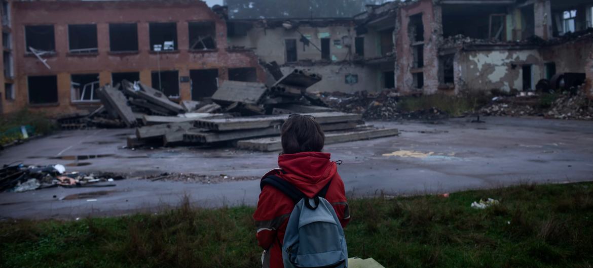 A child views devastated buildings during the war in Ukraine. 