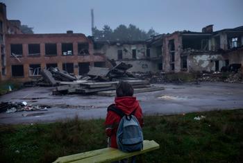 A child views devastated buildings during the war in Ukraine. 