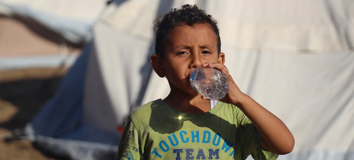 Un garçon de cinq ans boit de l'eau en bouteille livrée par l'UNICEF dans le camp de Khan Younis à Gaza.