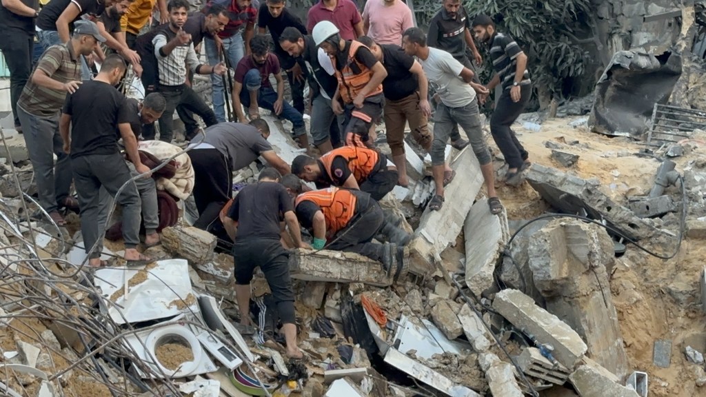 (من الأرشيف) أفراد قوات الدفاع المدني في غزة، يحاولون إنقاذ الناس من تحت أنقاض مبنى هُدم بسبب قصف جوي.