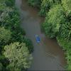 Vista aérea de um barco em um rio que flui pela floresta amazônica.