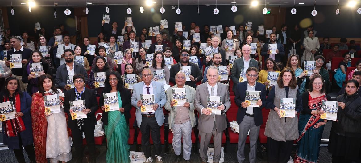 भारत में एक प्रेस कॉन्फ्रेंस में लोगों का एक समूह बहुभाषी शिक्षा पर UNESCO की एक नई रिपोर्ट की प्रतियां पकड़े हुए है।