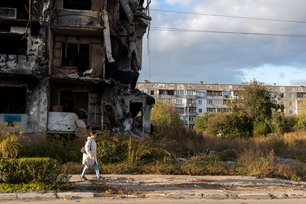 A woman walks past a destroyed apartment building in western Ukraine.