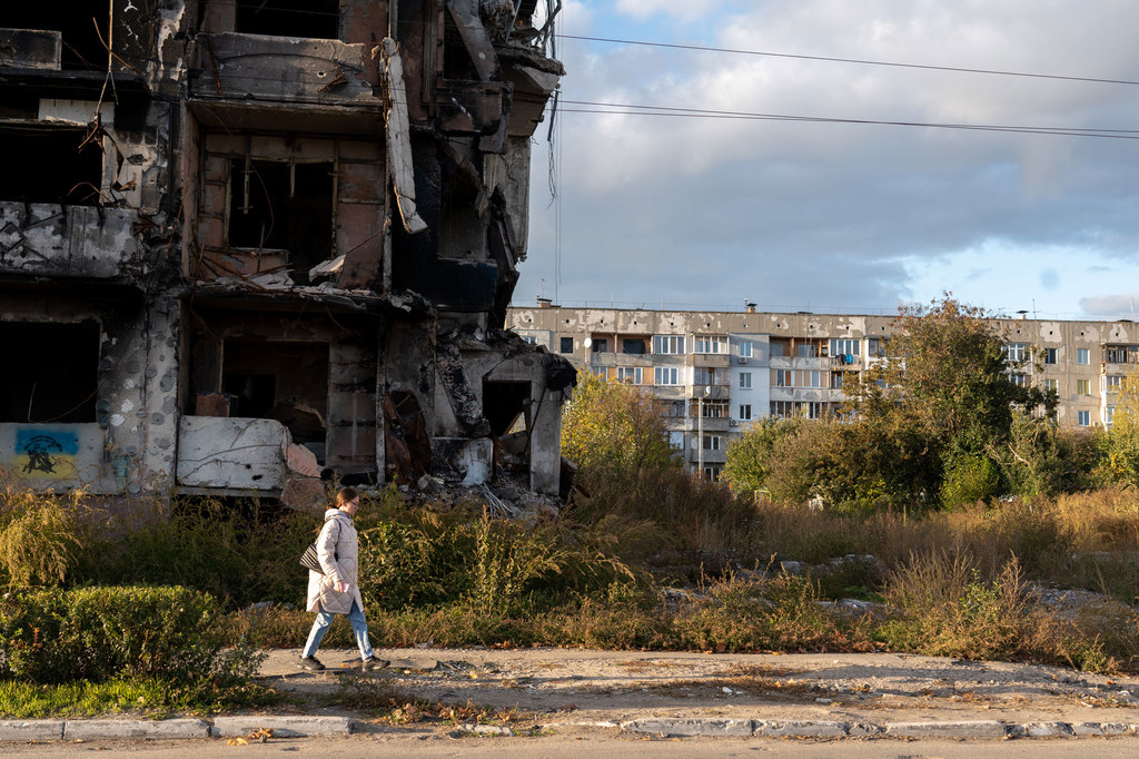 A woman walks past a destroyed apartment block in western Ukraine. A woman walks past a destroyed apartment block in western Ukraine.