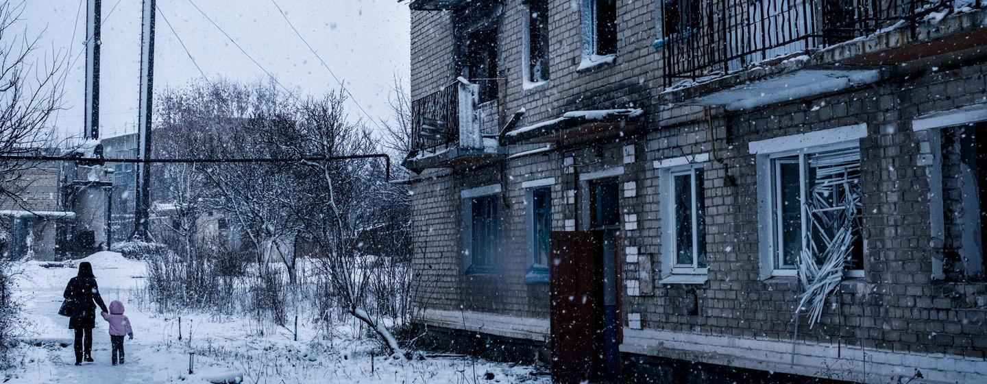 Des personnes marchent devant un immeuble résidentiel détruit par des tirs d'obus à Marinka, dans l'oblast de Donetsk, en Ukraine.