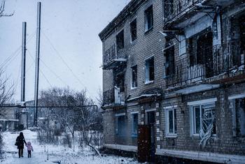 Des personnes marchent devant un immeuble résidentiel détruit par des tirs d'obus à Marinka, dans l'oblast de Donetsk, en Ukraine.