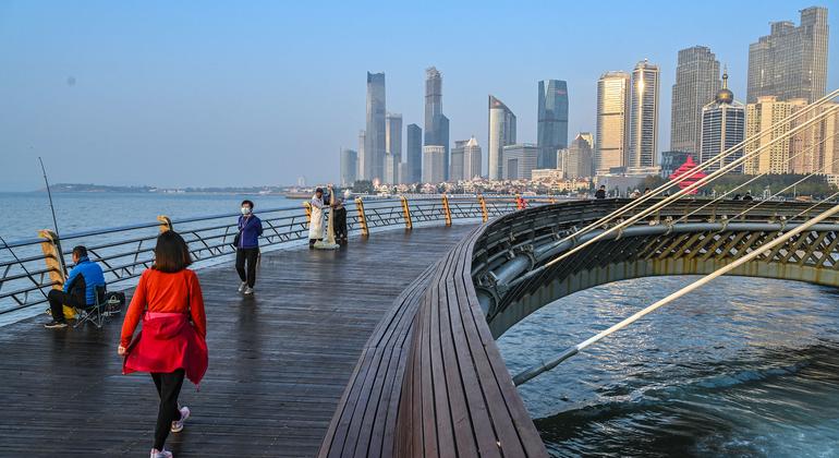 Pessoas caminham em uma ponte em um distrito de “energia inteligente e de baixo carbono” de Qingdao, na China